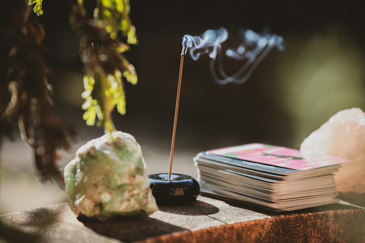 Humo de incienso flota entre un cristal y cartas del tarot.