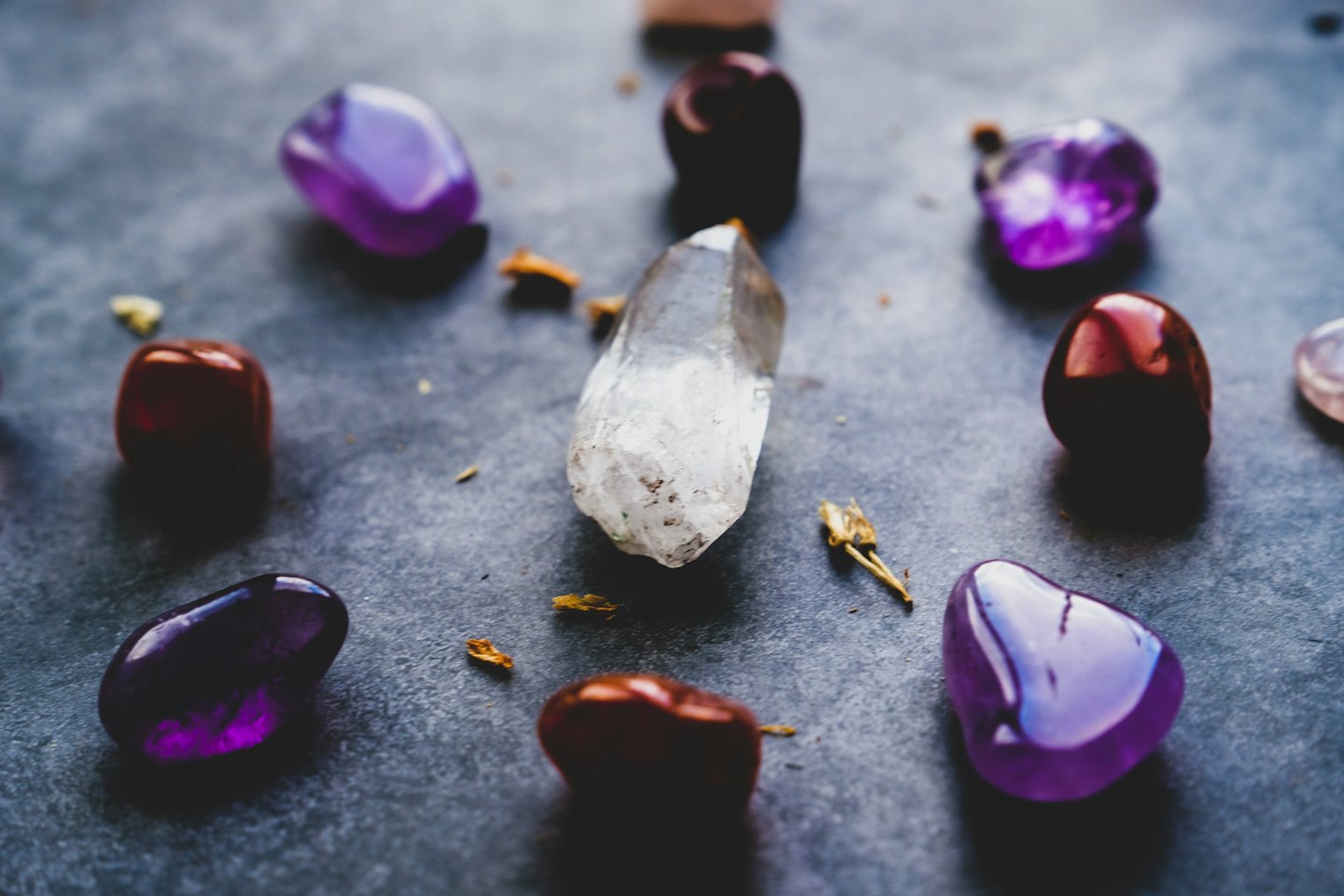 Piedras preciosas en bruto y pulidas esparcidas sobre una superficie oscura.